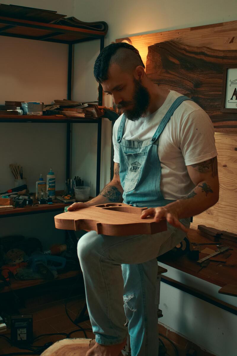 Woodworker holding a handcrafted wooden guitar he built from plans